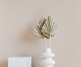 White vase with decorative leaves on shelf